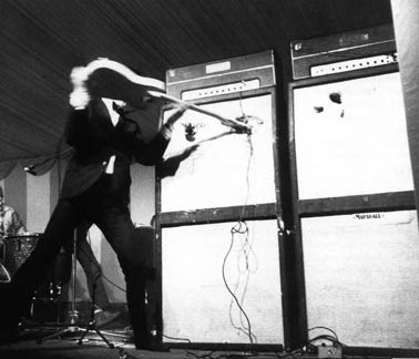 In July 1966, with Tone Bender MkI fuzz pedal visible at bottom right. Cabinets are two Marshall 8×12 cabinets (being impaled by a Fender Telecaster fitted with a non-Fender rosewood neck). Amps are two Marshall JTM45 100 Tremolo (1959T JTM100 Tremolo Super Lead) amplifier heads.