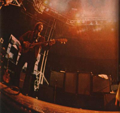 Ca. 1975, Sunn rig (with amplifier rack barely visible at far left): two Sunn 4×12 speaker cabs (outside top), two Sunn 312 3×12 speaker cabs (inside top), two Sunn 1×18 speaker cabs (outside bottom), two Sunn W 1×18 reflex bins (inside bottom).