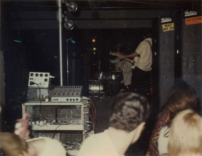 10 August 1968, Jaguar Club, St. Charles, Ill., stage-side view of Ackuset PA rig: rack with four power amps (Dynakit 60w?), bottom; an Ackuset 6-channel mixer with sliders, top right, and Ackuset All Sound tape echo, top left. The band in the background is the second warmup band. (Photo: Rick Giles)