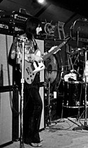 Ca. 1971, with custom-color (possibly orange) Gibson Thunderbird IV bass (“Non-Reverse”-style). Amp rig is Sunn Coliseum Bass and Sunn Coliseum Lead heads, two Sunn 4×12s and two Sunn 1×18s.