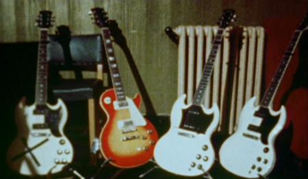 Ca. October 1973, UK, backstage, with three capoed Polaris White Gibson SG Specials and a cherry sunburst Les Paul Deluxe. Left and right are pre-1966 models; center-right is 1966–1970 model.